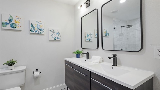 bathroom with a tile shower, vanity, and toilet