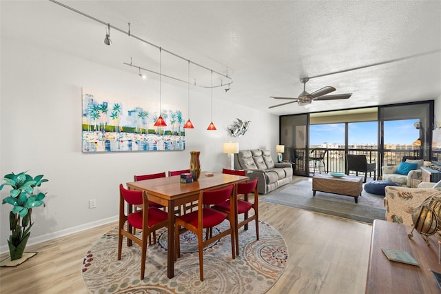 dining space featuring a textured ceiling, light hardwood / wood-style flooring, ceiling fan, and rail lighting