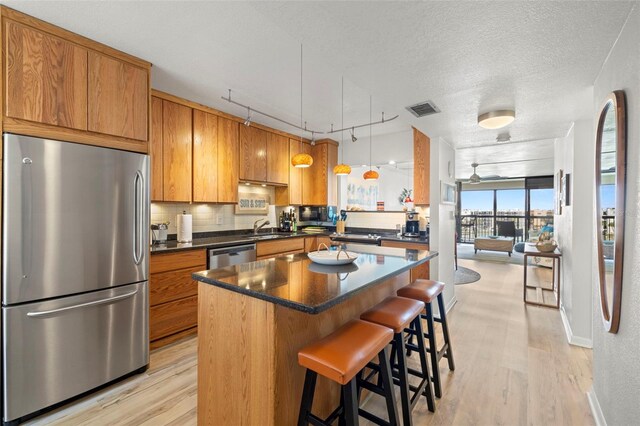 kitchen featuring a center island, appliances with stainless steel finishes, rail lighting, light hardwood / wood-style flooring, and hanging light fixtures