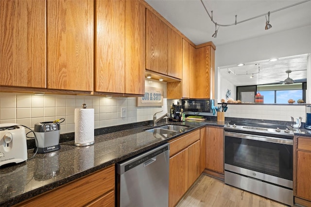 kitchen with stainless steel appliances, brown cabinets, a sink, and decorative backsplash