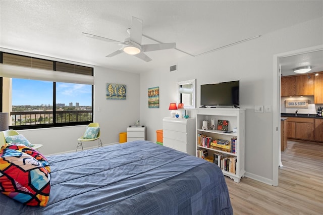 bedroom featuring a textured ceiling, a ceiling fan, visible vents, baseboards, and light wood-type flooring