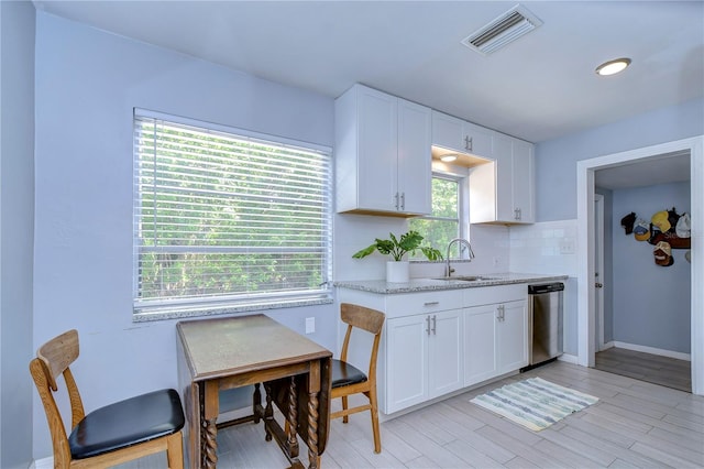 kitchen with a wealth of natural light, sink, decorative backsplash, and white cabinets