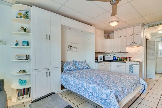 bedroom featuring light tile patterned floors, a drop ceiling, and a sink