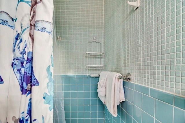 bathroom featuring tiled shower and tile walls