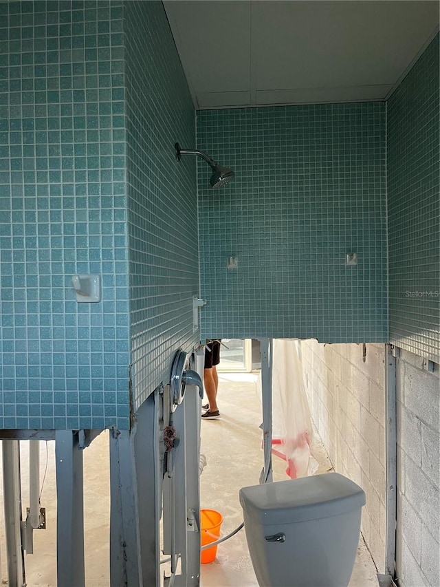 bathroom with toilet and tile walls