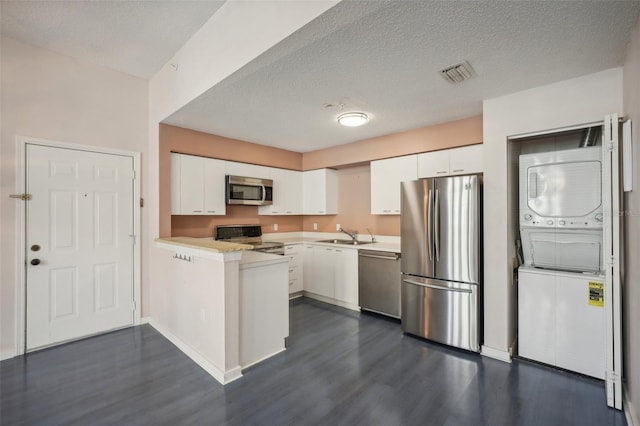 kitchen featuring stainless steel appliances, stacked washer and dryer, dark hardwood / wood-style floors, and white cabinets