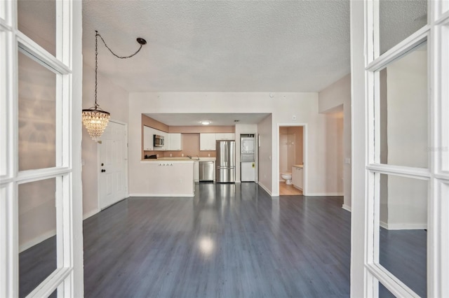 unfurnished living room with a notable chandelier, a textured ceiling, and dark hardwood / wood-style floors