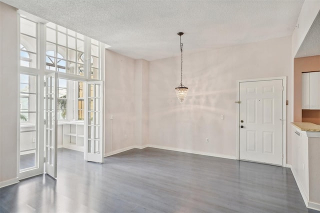 unfurnished dining area featuring a textured ceiling, dark hardwood / wood-style flooring, and a towering ceiling