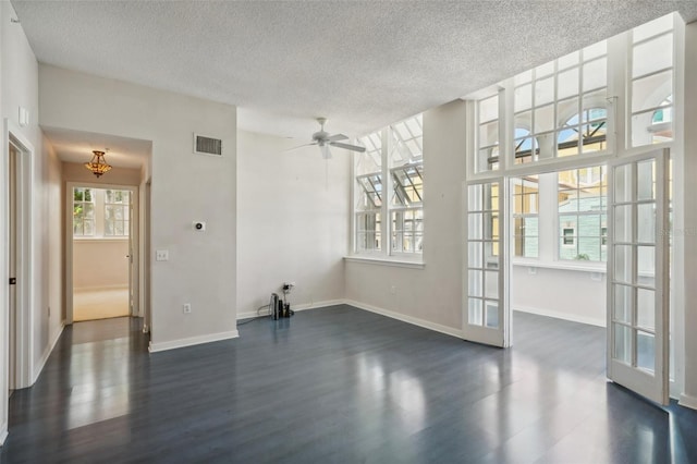 spare room featuring a wealth of natural light, dark wood-type flooring, and a textured ceiling