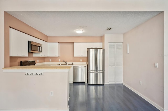 kitchen featuring appliances with stainless steel finishes, white cabinetry, dark hardwood / wood-style flooring, and sink