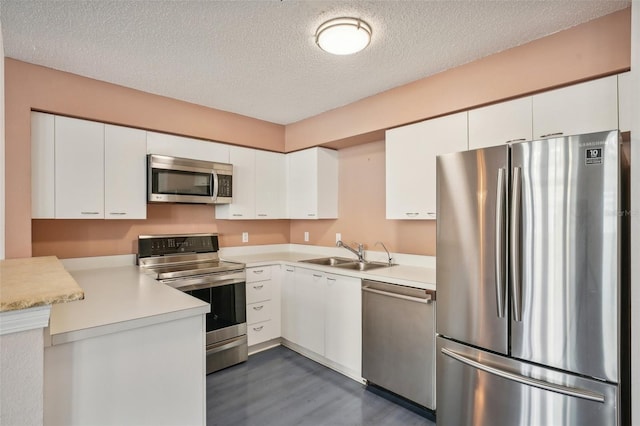 kitchen with sink, appliances with stainless steel finishes, dark wood-type flooring, a textured ceiling, and white cabinets