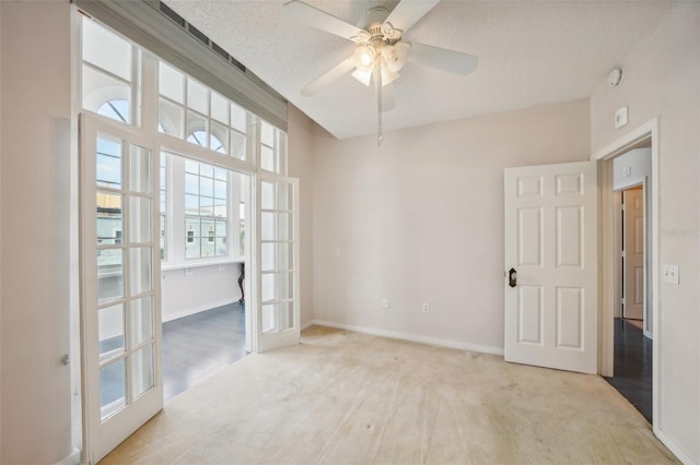 carpeted empty room featuring ceiling fan, french doors, and a textured ceiling