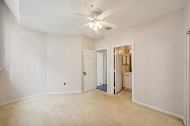 unfurnished bedroom featuring ceiling fan, light tile patterned flooring, and ensuite bathroom