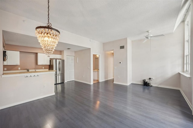 unfurnished living room featuring ceiling fan with notable chandelier, hardwood / wood-style floors, and a textured ceiling