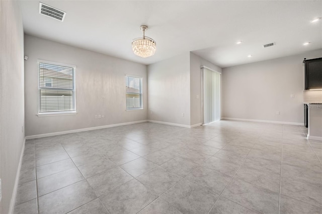 empty room featuring an inviting chandelier and light tile patterned flooring