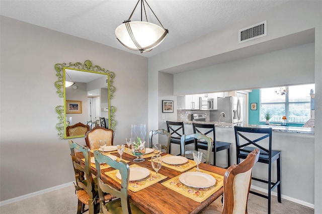 carpeted dining area featuring a textured ceiling and sink