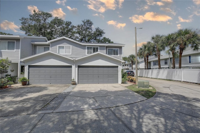 view of front of property with a garage, fence, concrete driveway, and stucco siding