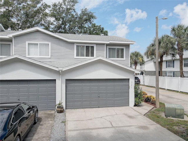 view of property featuring a garage, a shingled roof, fence, driveway, and stucco siding