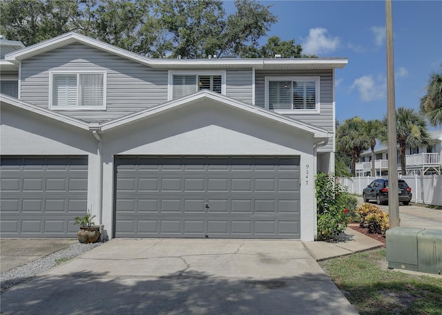 view of front facade featuring a garage, concrete driveway, fence, and stucco siding