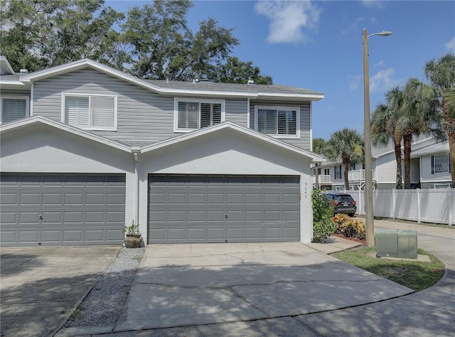 view of front facade featuring driveway, fence, and stucco siding