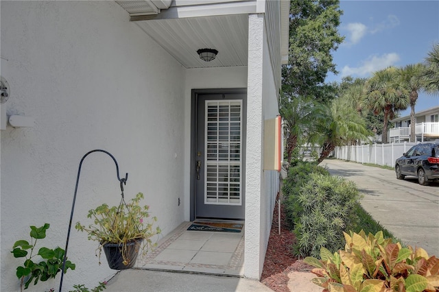 entrance to property with fence and stucco siding