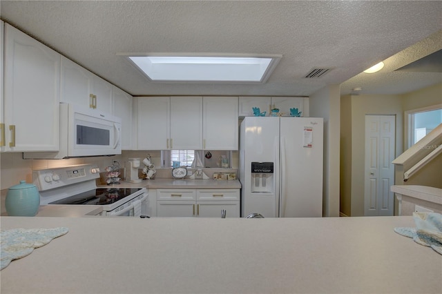 kitchen featuring a textured ceiling, white appliances, white cabinetry, and a skylight