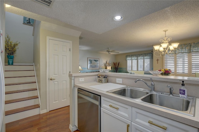 kitchen featuring dishwasher, sink, white cabinets, wood-type flooring, and hanging light fixtures