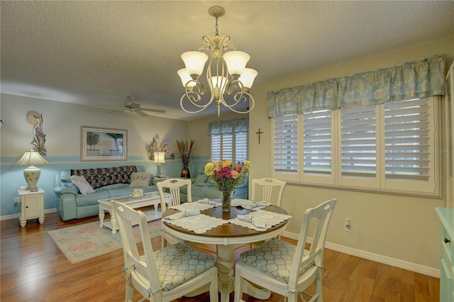 dining space with a textured ceiling, ceiling fan with notable chandelier, and hardwood / wood-style flooring