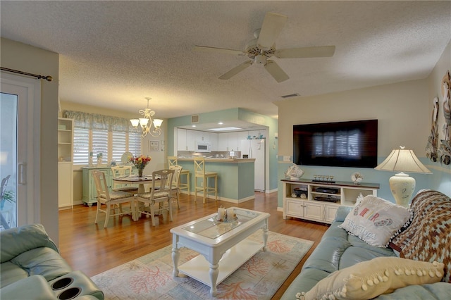 living room featuring ceiling fan with notable chandelier, a textured ceiling, and light hardwood / wood-style floors