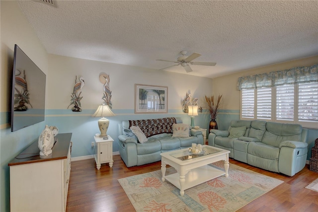 living room with ceiling fan, wood-type flooring, and a textured ceiling