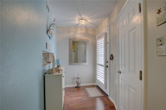 entryway featuring plenty of natural light, a textured ceiling, baseboards, and wood finished floors