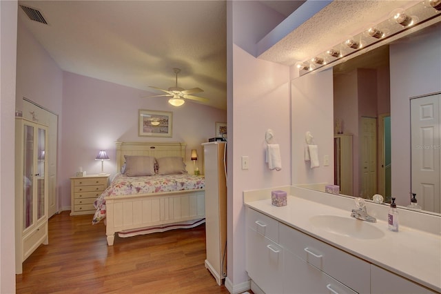 bathroom featuring visible vents, a ceiling fan, vaulted ceiling, vanity, and wood finished floors