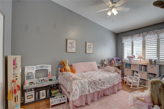 bedroom with lofted ceiling, ceiling fan, a textured ceiling, and wood finished floors