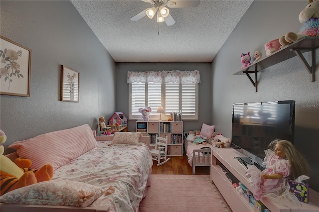 bedroom with a textured ceiling, ceiling fan, hardwood / wood-style floors, and vaulted ceiling