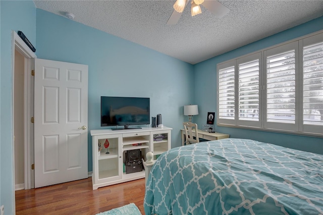 bedroom with lofted ceiling, a textured ceiling, a ceiling fan, and wood finished floors