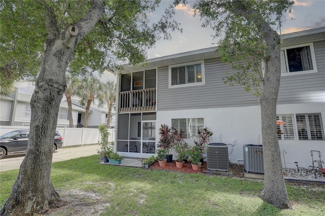 back of property featuring stucco siding, a lawn, fence, and central AC unit