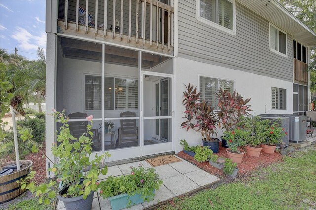 rear view of property featuring a balcony, central AC unit, and a sunroom