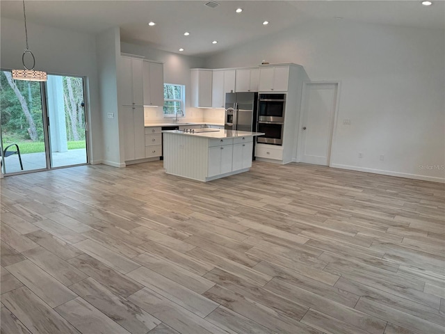 kitchen featuring appliances with stainless steel finishes, light hardwood / wood-style floors, high vaulted ceiling, white cabinets, and a kitchen island