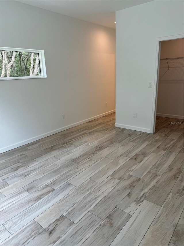 unfurnished bedroom featuring a spacious closet, a closet, and light wood-type flooring