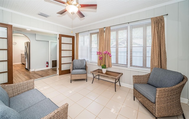 living area featuring ceiling fan, light tile patterned floors, and crown molding