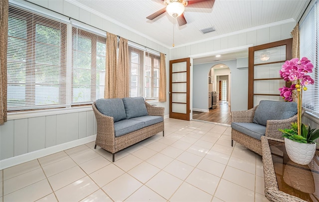 living area with ceiling fan, crown molding, and tile patterned floors