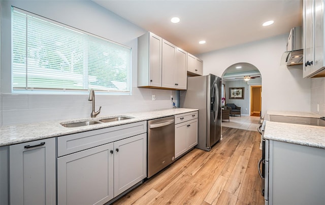 kitchen with backsplash, sink, light hardwood / wood-style floors, ceiling fan, and stainless steel appliances