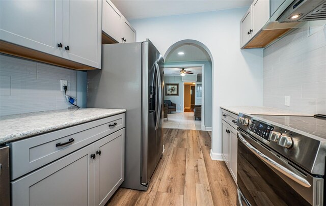 kitchen featuring ceiling fan, decorative backsplash, light hardwood / wood-style floors, and stainless steel appliances