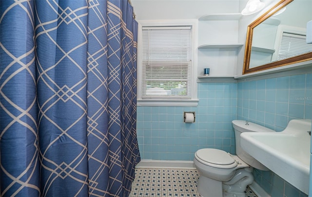 bathroom featuring toilet, a sink, tile walls, and a shower with shower curtain