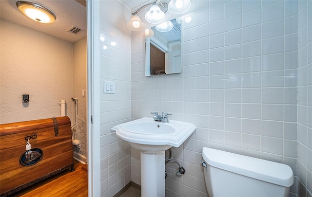 bathroom with tile walls, toilet, and wood-type flooring