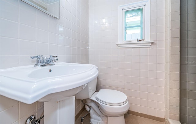 bathroom with toilet and tile walls