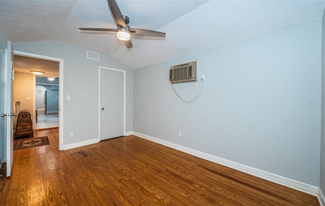 unfurnished bedroom featuring hardwood / wood-style flooring, a wall mounted air conditioner, a textured ceiling, ceiling fan, and lofted ceiling