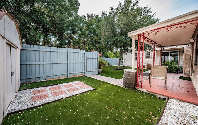 view of yard with a patio area, a fenced backyard, and an outdoor structure