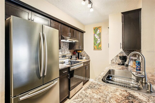 kitchen with decorative backsplash, appliances with stainless steel finishes, dark brown cabinets, a textured ceiling, and sink