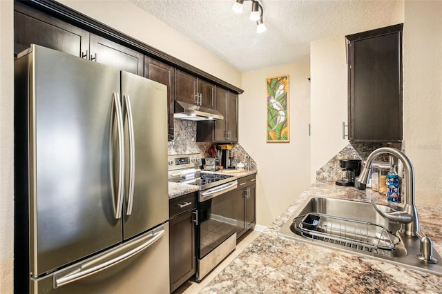 kitchen with light countertops, appliances with stainless steel finishes, a sink, dark brown cabinetry, and under cabinet range hood